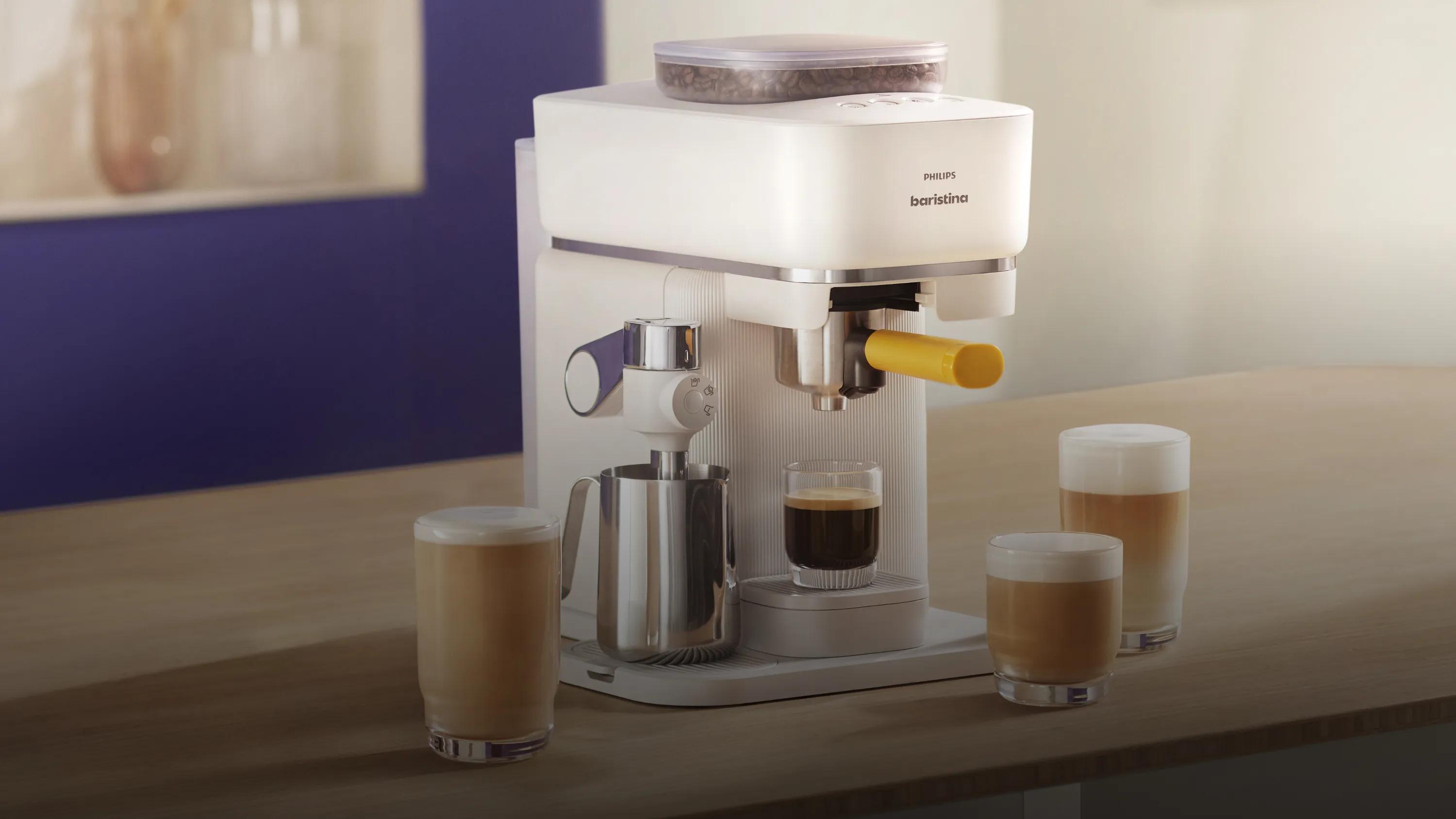 Philips Baristina Latte préparant un cappuccino avec sa lance à lait intégrée à côté de boissons de style café