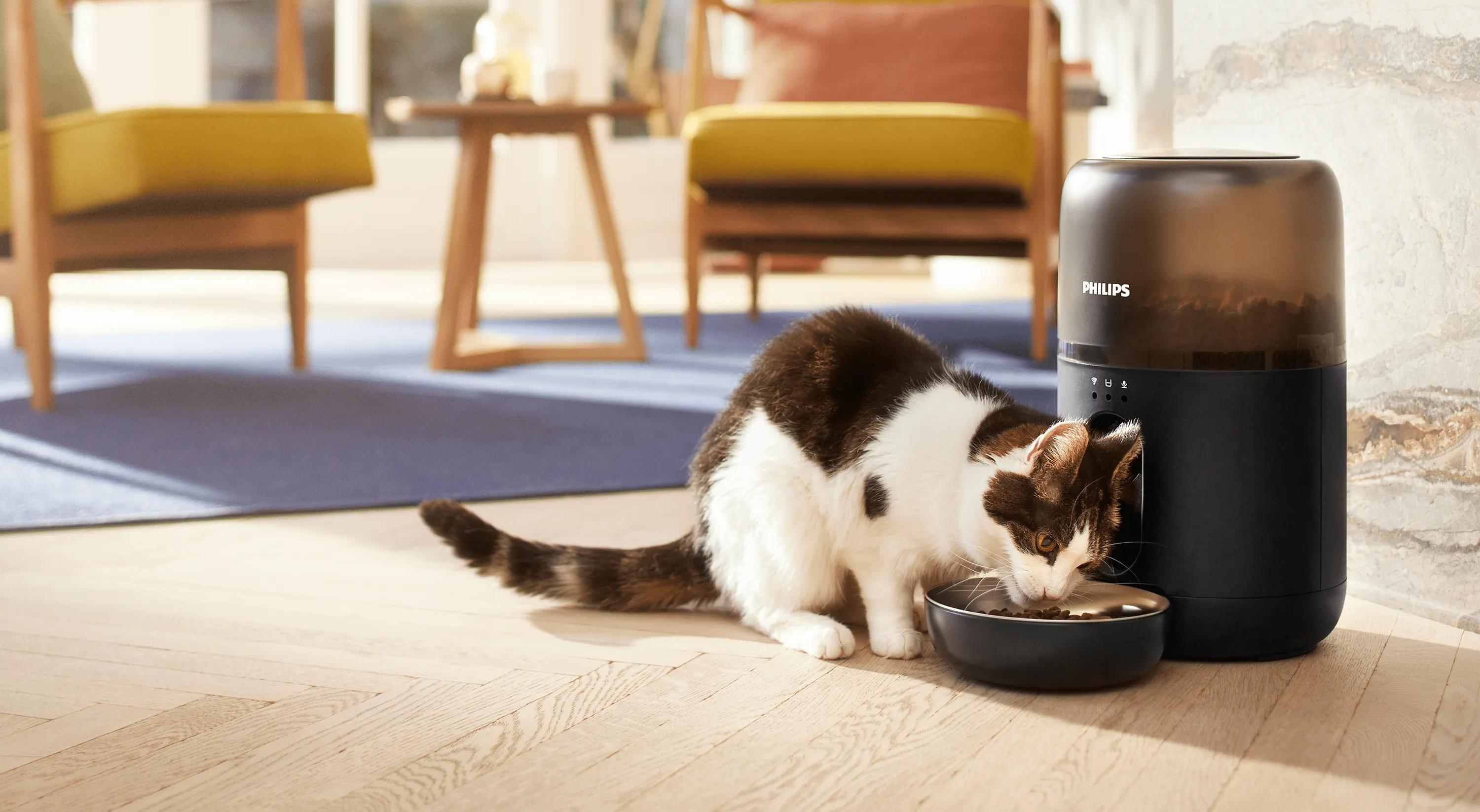 Katze genießt eine Mahlzeit aus einem Philips Pet Care Futterautomat. Mit Portionskontrolle, App-Konnektivität und schlankem Design für moderne Tierbesitzer.