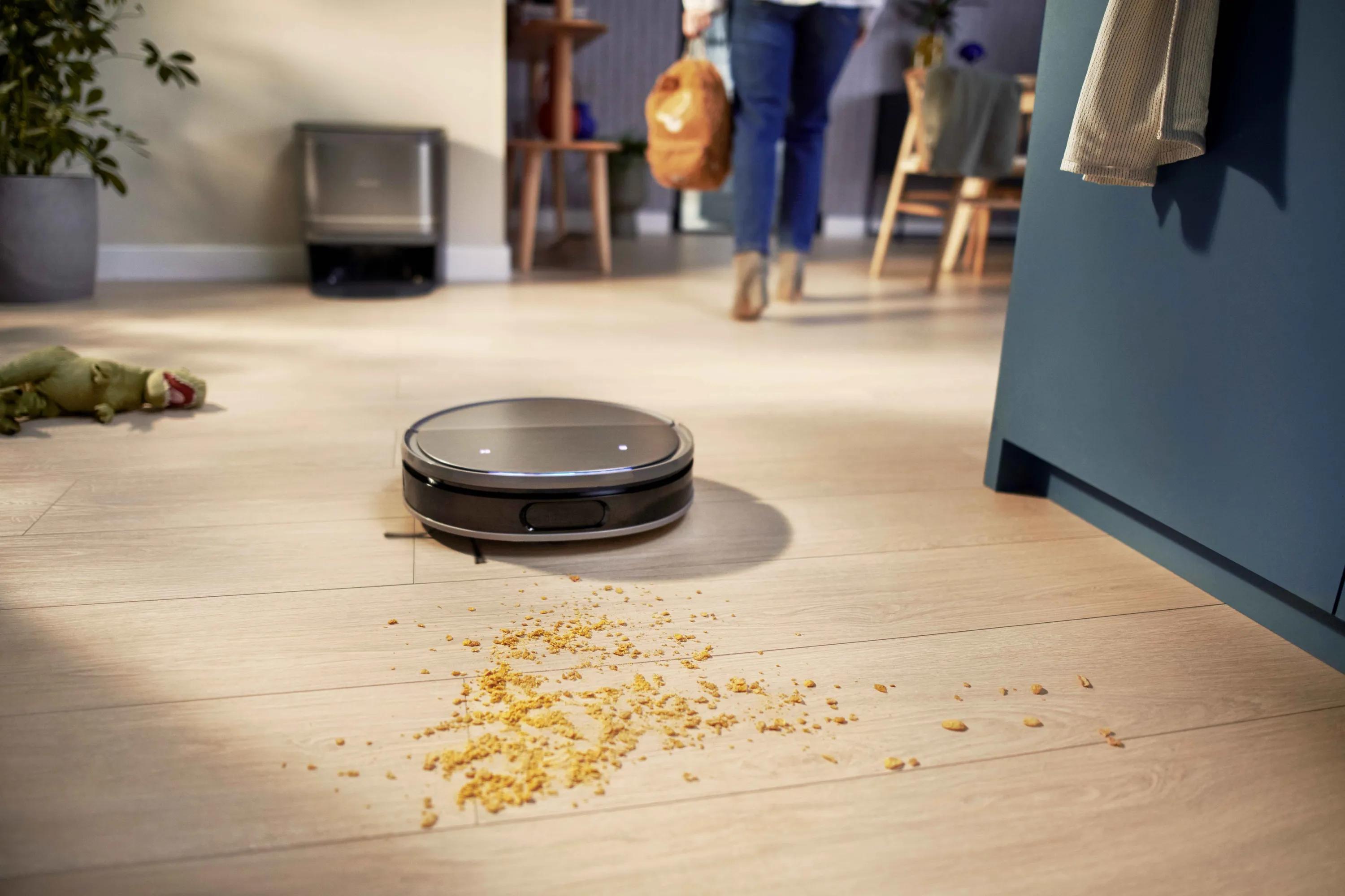 Philips Robot 9000 städar enkelt smulor på ett ljust trägolv. Denna Philips golvvårdsinnovation säkerställer perfekt automatiserad rengöring, vilket förenklar hemunderhållet.