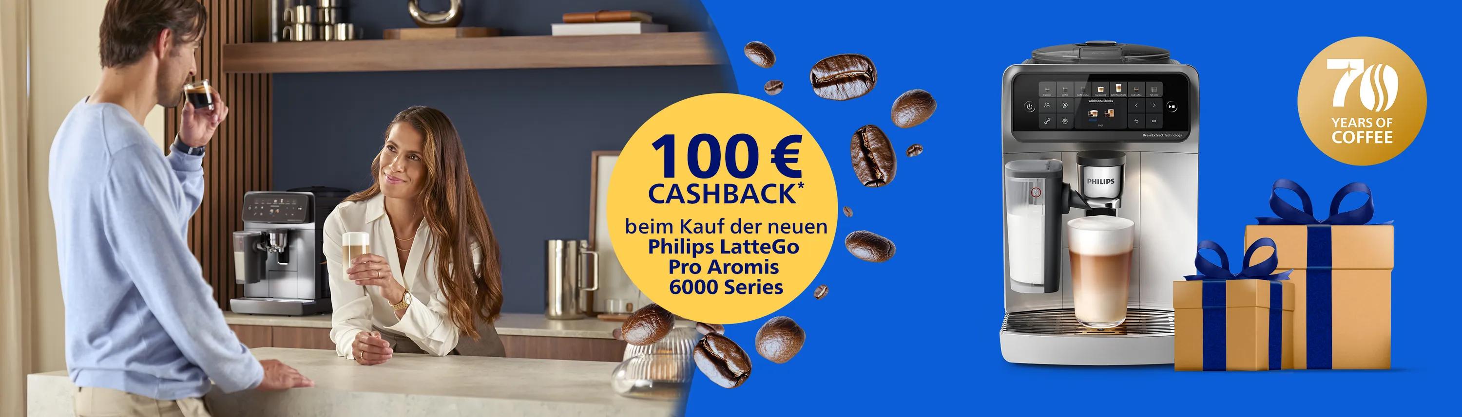 Espressomaschine Philips LatteGo Pro Aromis der Serie 6000 mit 100 € Cashback-Angebot, Geschenkboxen und einem Paar, das in einer Küche Kaffee trinkt.