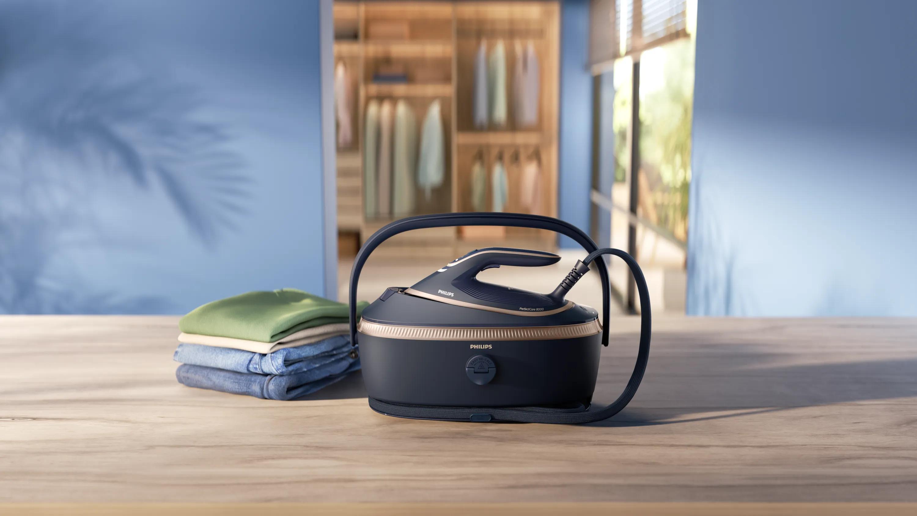Philips PerfectCare 8000 steam generator with clothes on wooden table in modern laundry room.